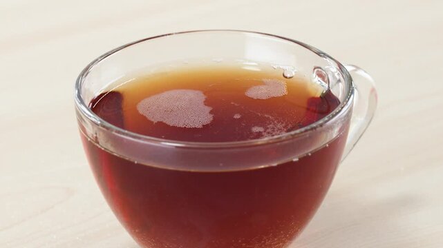 Pouring White Sugar into a Clear Glass Cup of Hot Black Tea