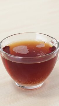 Pouring White Sugar into a Glass Cup of Fresh Black Tea