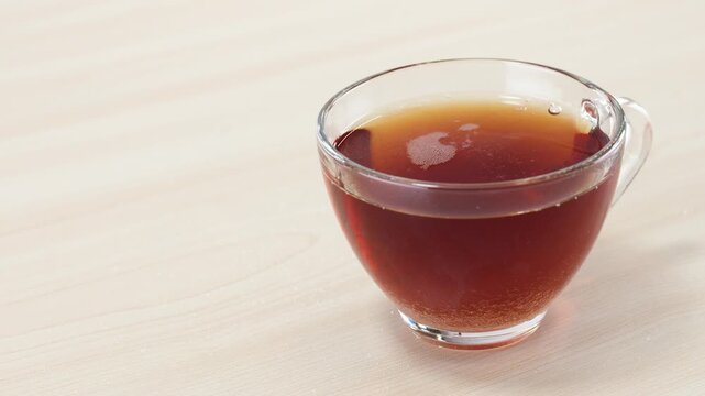 Pouring White Sugar into a Clear Glass Cup of Hot Black Tea