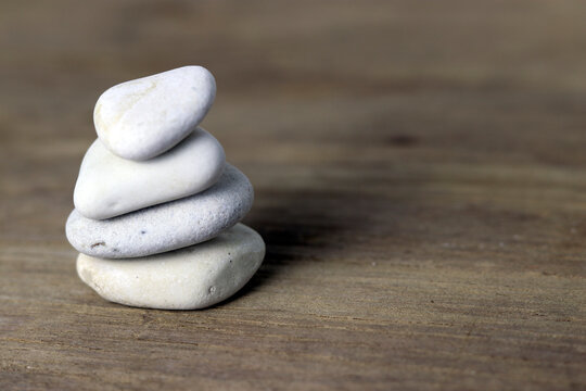 Stack of smooth white and gray stones on a rustic wooden surface, symbolizing balance, harmony, meditation, mindfulness, peace, and natural simplicity