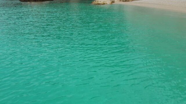 Woman meditating at white pebble beach with turquoise sea water on Kefalonia coast, Greece