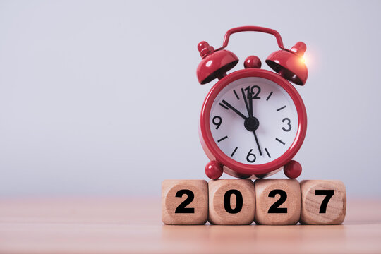 Red alarm clock above 2027 wooden blocks symbolizes New Year countdown, deadline, time management, planning, schedule and upcoming goals with clean copy space for business or calendar concepts.