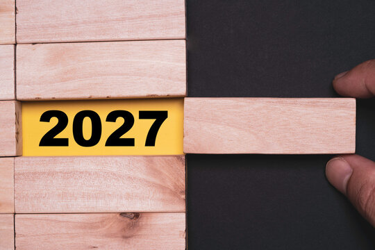 Hand removes a wooden block to reveal 2027 symbolizing New Year transition, future planning, business strategy, change, opportunity, goals and preparation for a successful year ahead.