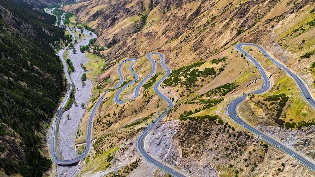 Aerial view of the winding Duku Highway passing through an arid mountain valley in Xinjiang, China