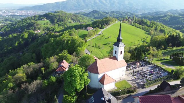 Aerial drone view of St. Urban's Church in &Scaron;ober near Maribor, Slovenia, surrounded by green hills, forests and rural countryside.