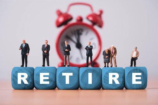 Retirement concept with senior people standing on wooden blocks and an alarm clock representing retirement planning, pension aging workforce, financial security, life transition and retirement time.