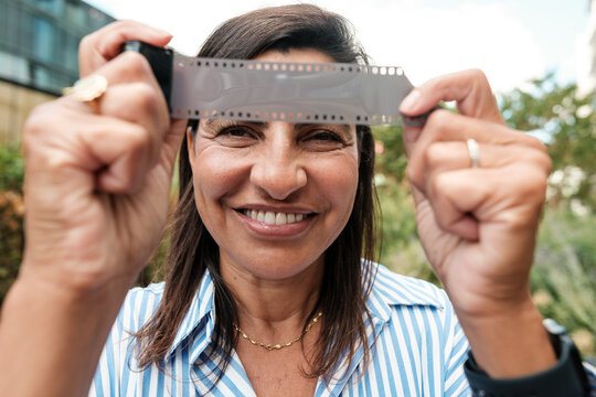 Smiling woman holding film strip appreciating retro photography