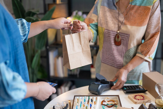 woman tapping credit card on EDC terminal for secure cashless payment in handmade shop using contactless card payment cashless society financial technology