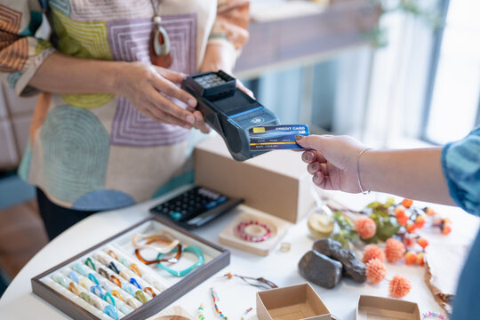 woman tapping credit card on EDC terminal for secure cashless payment in handmade shop using contactless card payment cashless society financial technology