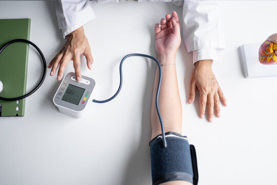 Female physician checking blood pressure of woman during routine health examination at modern medical clinic.