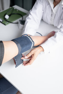 Female physician checking blood pressure of woman during routine health examination at modern medical clinic.
