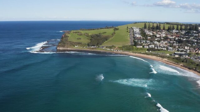 Aerial view of the scenic coastal tourist town of Gerringong with views of the famous Tasman Drive on the southern headland. Captured high above Werri surfing Beach on a sunny day on the NSW Coast.