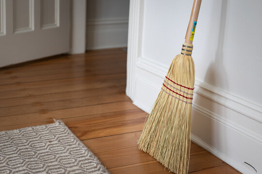Broom Resting Against White Wall Hardwood Floor