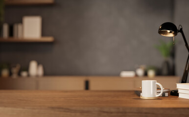 Naklejka na ściany i meble Close up of wooden desk with white mug, lamp and books in blurred modern office background.