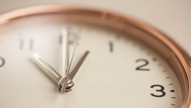 close up of wall clock hands showing time with gold rim frame
