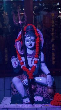Lord Shiva seated in a meditative posture, illuminated with deep blue light and surrounded by a mystical temple-like atmosphere.