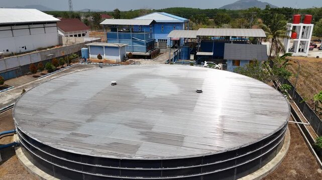 Large circular metal reservoir tank for water storage at an industrial processing facility