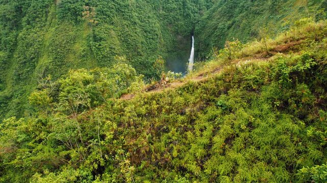 Traveler hiking along lush green cliffside with view of waterfall in Costa Rica