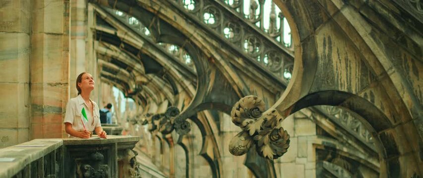 Tourist gazing at gothic architecture on Duomo Milan Cathedral rooftop in summer