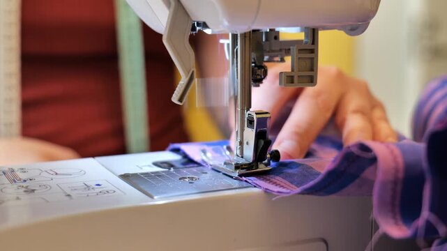 Precision tailoring work showing hands guiding checkered fabric through a sewing machine.