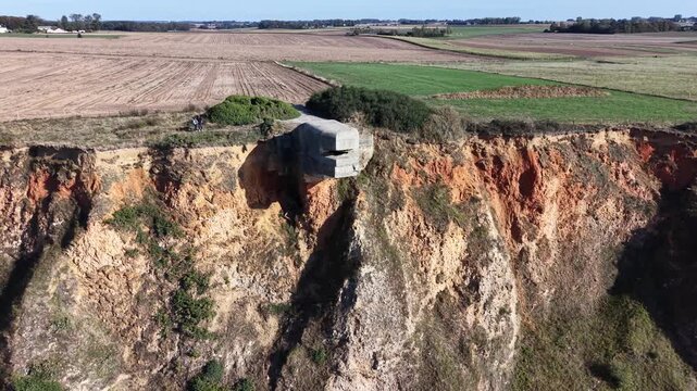 World War II concrete bunker built into the chalk cliffs of Normandy, surrounded by agricultural fields and coastal vegetation