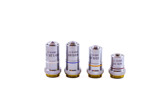 Set of four microscope objectives marked 100/1.25, 40/0.65, 10/0.25 and 4/0.10, all with 160/0.17 specifications, isolated on white.