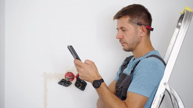 Man using smartphone during electrical outlet installation