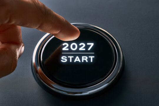 Human hand activating future start button for year 2027 new beginnings.