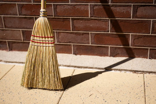 Straw Broom Against Brick Wall Sunny Day