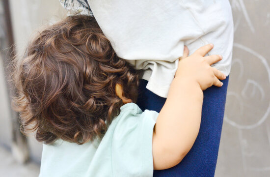 Toddler hides the face in big brother.