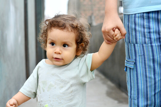 Cute toddler holds his mommy's hand.
