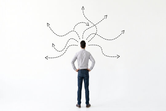 Man contemplating multiple diverging paths drawn on a white wall during indecision