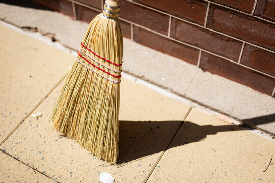 Straw Broom Standing Against Brick Wall