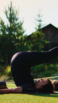 Woman practicing advanced outdoor yoga inversion pose on grass lawn in peaceful garden setting, focusing on balance, flexibility, mindfulness and core strength