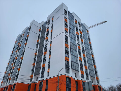 A new, beautiful multistory building with orange facade tiles against the backdrop of a gray winter sky.