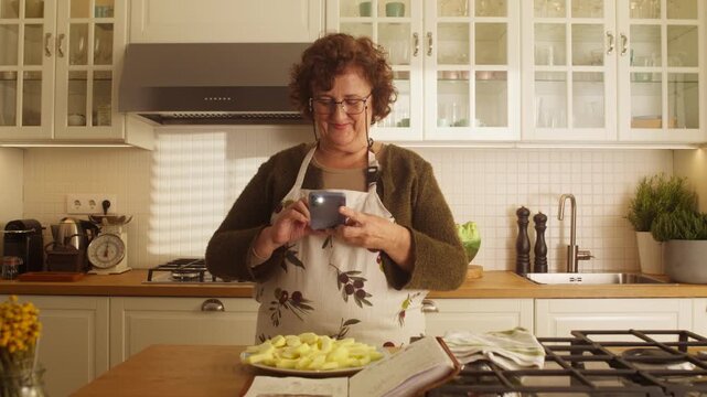 Camera pulls back as a woman photographs a homemade meal in a bright kitchen