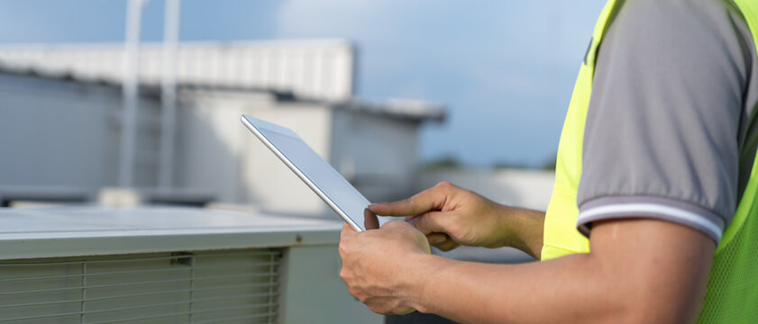 Asian maintenance engineer works on the roof of factory. contractor inspect compressor system and plans installation of air condition systems in construction. technology, online, mobile application.