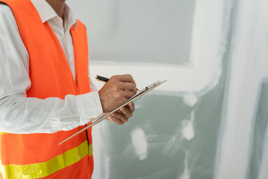 inspector or engineer is inspecting construction and quality assurance new house using a checklist. Engineers or architects or contactor work to build the house before handing it over to the homeowner