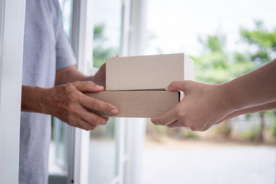Happy smiling woman receives boxes parcel from courier in front house. Delivery man send deliver express. online shopping, paper containers, takeaway, postman, delivery service, packages