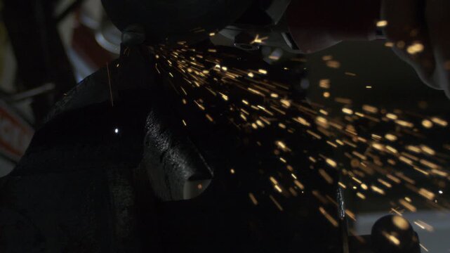 Close-up power grinding creates shower of golden sparks during equipment maintenance