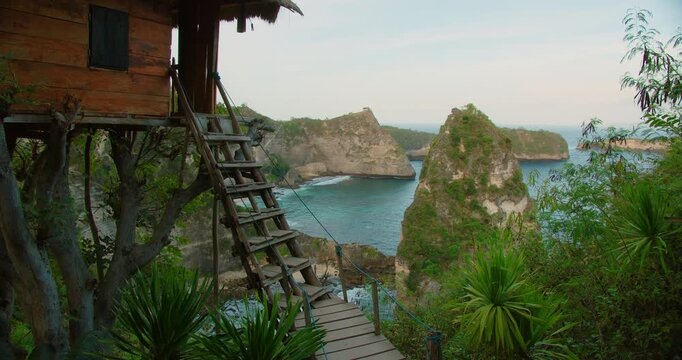 Wooden treehouse with stairs overlooks Diamond Beach and turquoise ocean on Nusa Penida Island
