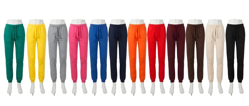 Twelve pairs of solid-color fleece sweatpants with drawstring waist, presented in a horizontal row on white mannequins, isolated on a white background.