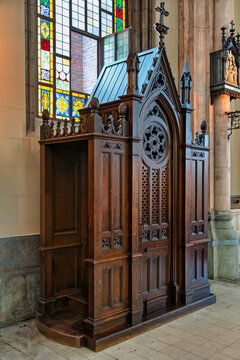 Ornate wooden confessional booth inside the historic St. Anthony of Padua Church in Istanbul, Turkey, with stained glass windows in the background