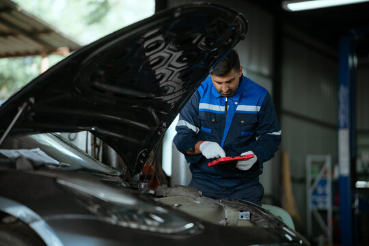 A uniformed maintenance technician is working on a vehicle inspection service. Vehicle repair and maintenance concept.