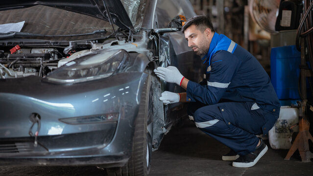 Mechanic working on car engine in auto repair shop