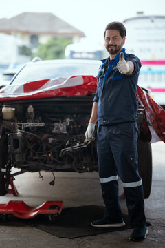 A male mechanic giving thumbs up smiling looking at camera with happy expression and satisfied with car repair service giving thumbs up in tire shop