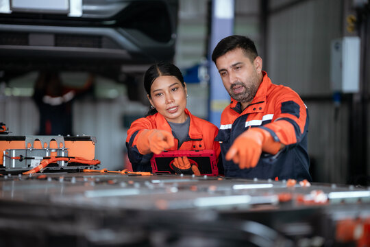 Professional auto mechanic working in auto repair shop, checking car engine.
