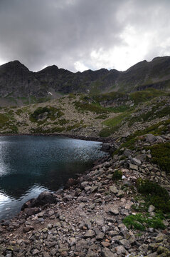 Mountain lake with rocky shore and overcast sky