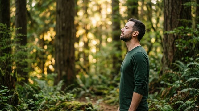 Man standing peacefully in forest breathing deeply with eyes closed