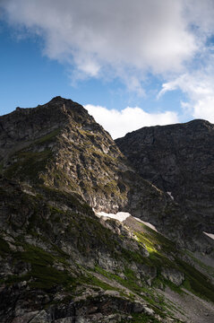 Rugged Mountain Peak with Snow Patches and Green Slopes